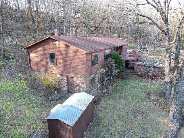 view of property exterior with a view of trees and a wooden deck