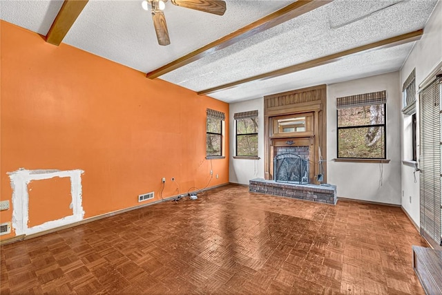 unfurnished living room with a brick fireplace, beam ceiling, visible vents, and a textured ceiling