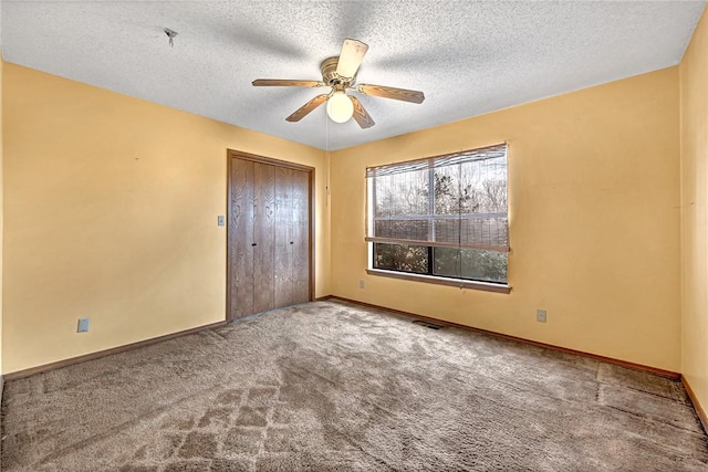 unfurnished bedroom with a textured ceiling, carpet floors, a closet, and baseboards