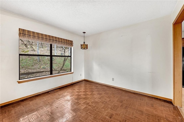 empty room with baseboards, visible vents, and a textured ceiling