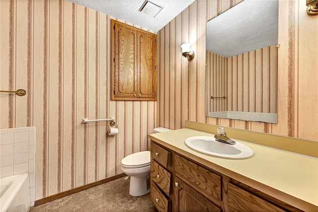 bathroom with wallpapered walls, toilet, a bathing tub, a textured ceiling, and vanity