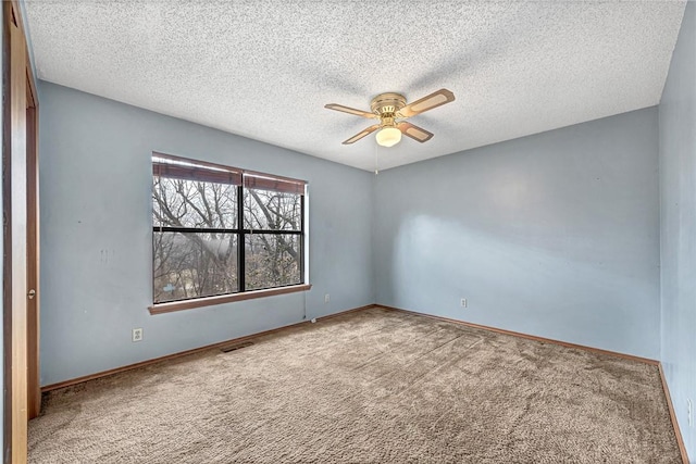 carpeted empty room with a ceiling fan, visible vents, a textured ceiling, and baseboards