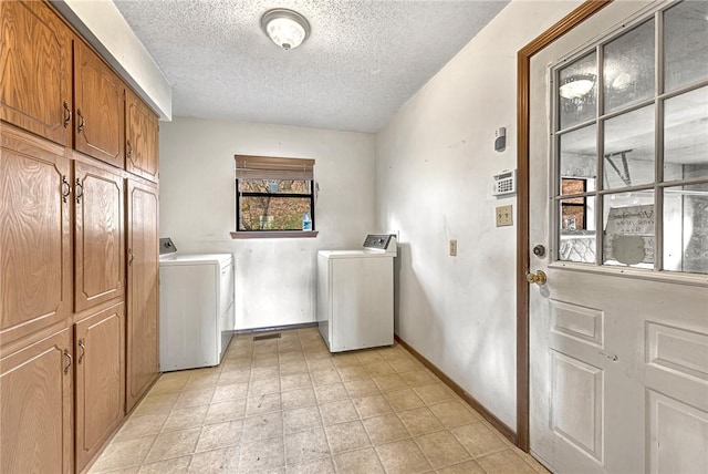 washroom with a textured ceiling, washing machine and clothes dryer, cabinet space, and baseboards