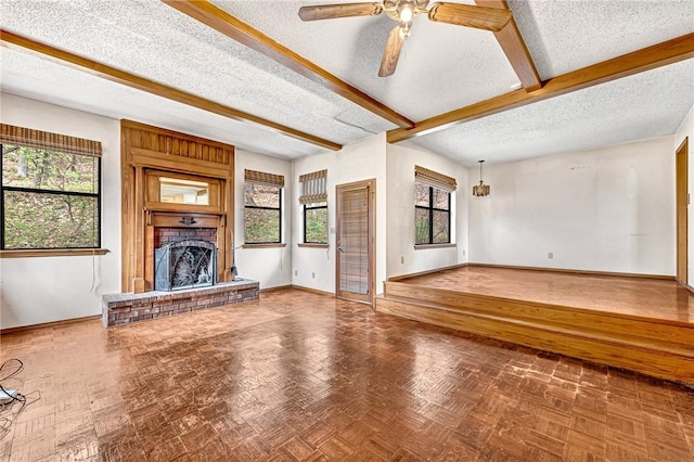 unfurnished living room with baseboards, ceiling fan, beamed ceiling, a textured ceiling, and a brick fireplace