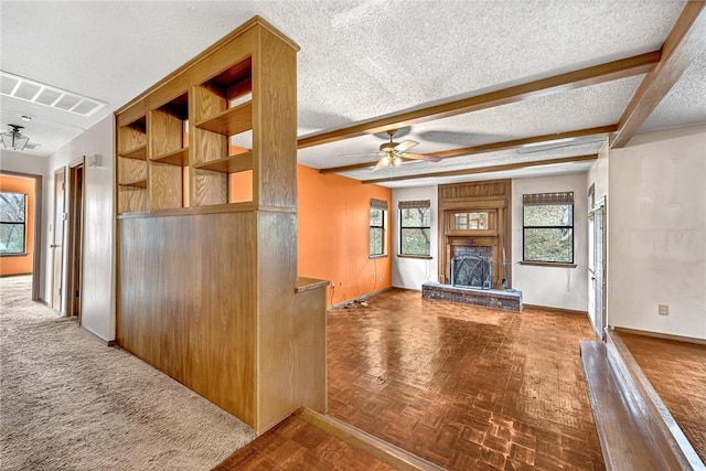 interior space featuring visible vents, a brick fireplace, ceiling fan, a textured ceiling, and beamed ceiling