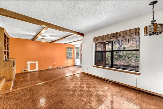 empty room with a textured ceiling, beamed ceiling, visible vents, and baseboards