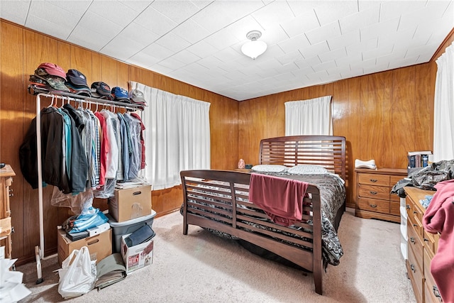 bedroom with a closet, light colored carpet, and wood walls