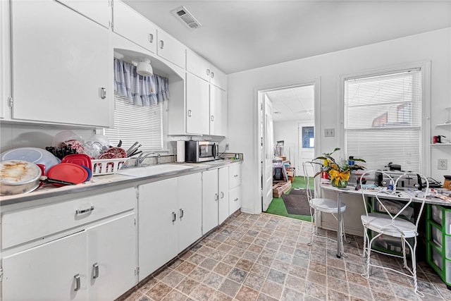 kitchen featuring light tile floors, white cabinetry, and sink