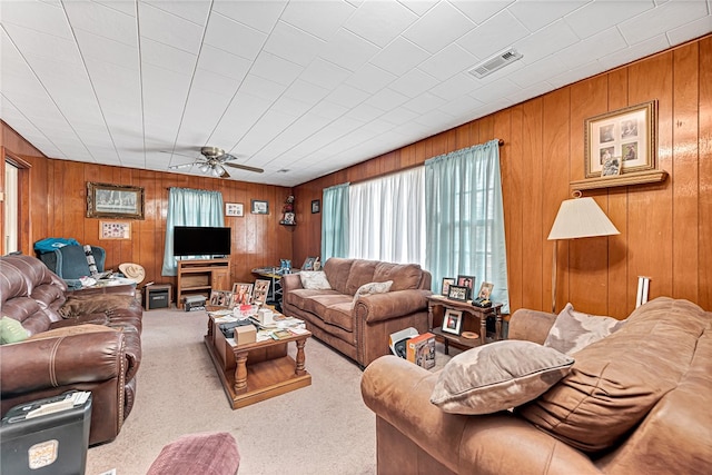 carpeted living room with ceiling fan and wood walls