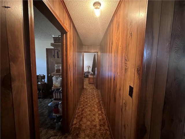 corridor with a textured ceiling and wood walls