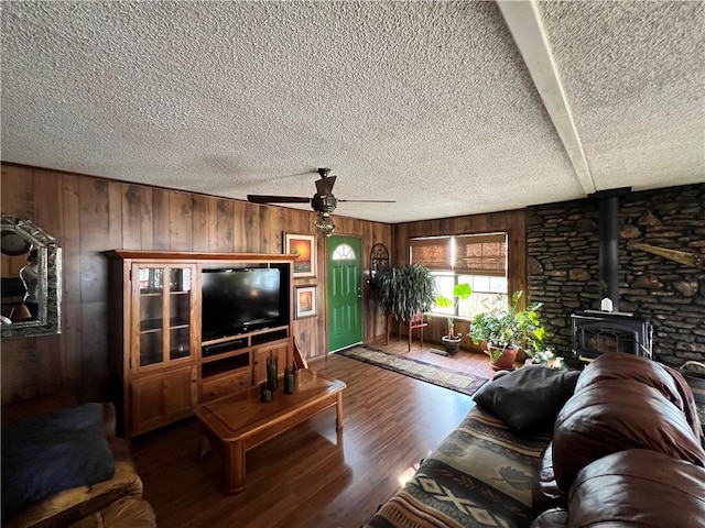 living room featuring ceiling fan, a wood stove, wood-type flooring, and wood walls