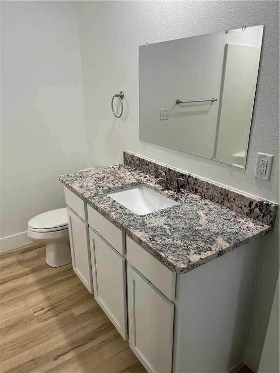 bathroom with toilet, vanity, and wood-type flooring