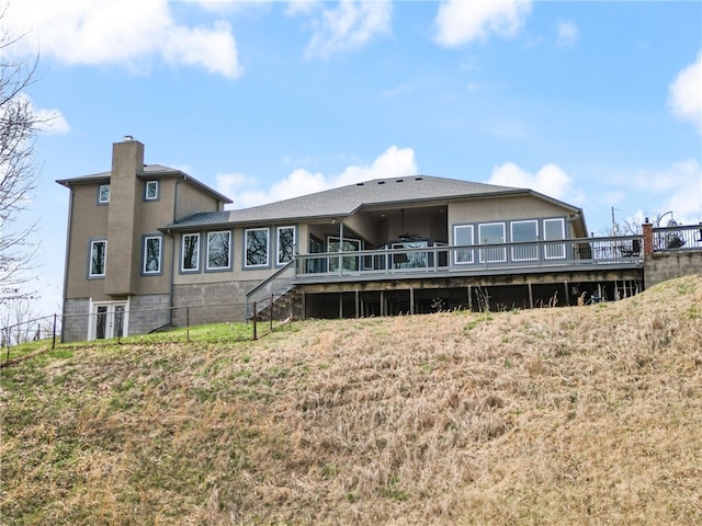 back of property featuring a wooden deck and a yard