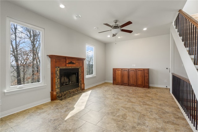 unfurnished living room with a tile fireplace and ceiling fan