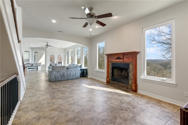 unfurnished living room with ceiling fan, a fireplace, and french doors