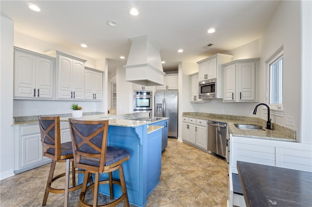 kitchen with a breakfast bar, sink, white cabinets, a kitchen island, and stainless steel appliances