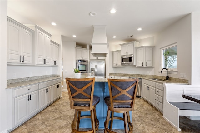 kitchen featuring a center island, a breakfast bar area, sink, white cabinetry, and appliances with stainless steel finishes