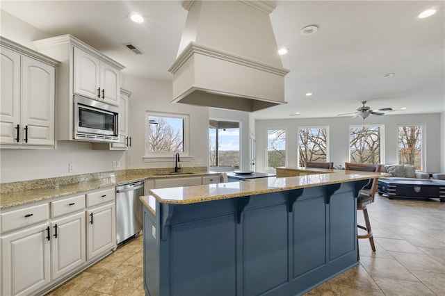 kitchen with white cabinetry, a kitchen island, stainless steel appliances, and a breakfast bar