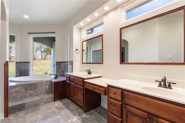 bathroom with tiled tub and vanity