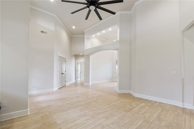 empty room featuring ceiling fan, light wood-type flooring, crown molding, and high vaulted ceiling