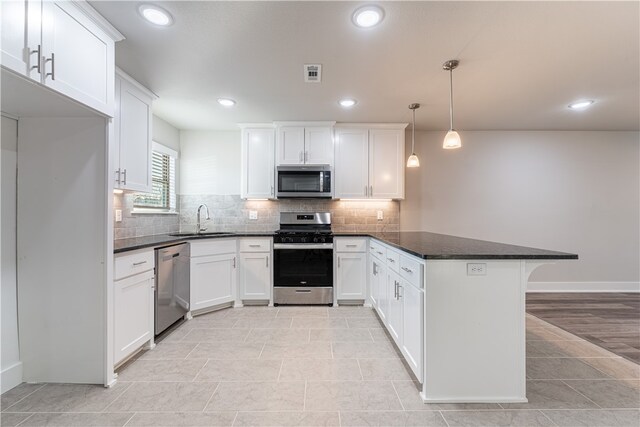 kitchen featuring decorative light fixtures, appliances with stainless steel finishes, tasteful backsplash, white cabinets, and light tile floors