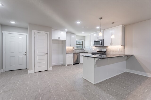 kitchen with stainless steel appliances, light tile flooring, kitchen peninsula, white cabinetry, and hanging light fixtures