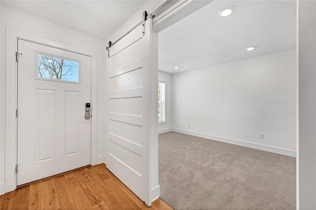 entryway featuring recessed lighting, a barn door, baseboards, and light wood-type flooring