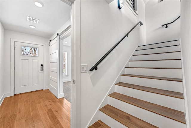 foyer with visible vents, stairs, light wood-style floors, and a barn door