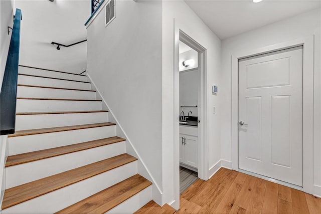 stairs with visible vents, baseboards, and wood finished floors