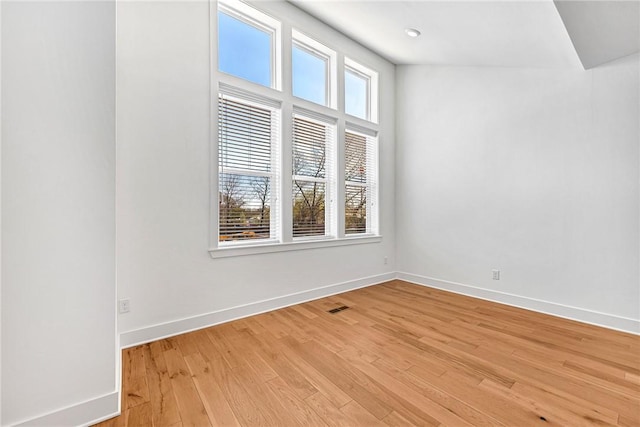 spare room featuring visible vents, light wood-type flooring, and baseboards