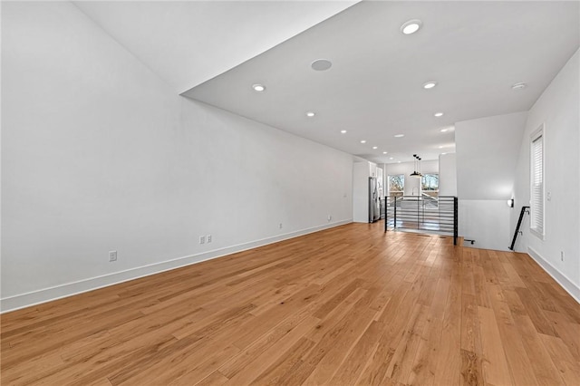 unfurnished living room with recessed lighting, baseboards, and light wood finished floors