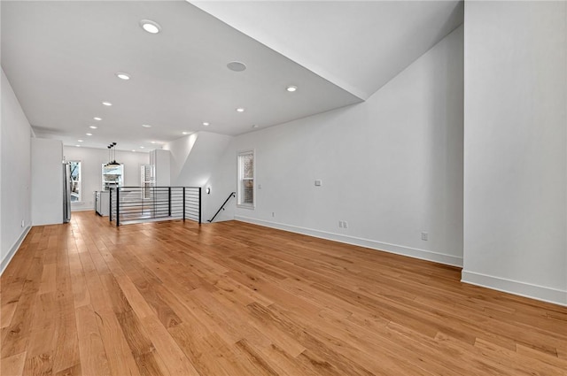 unfurnished living room with a wealth of natural light, recessed lighting, light wood-style flooring, and baseboards