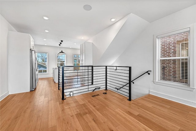 hall featuring an upstairs landing, recessed lighting, and light wood-style floors