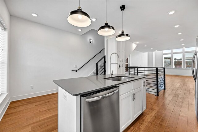 kitchen featuring pendant lighting, dishwasher, sink, white cabinetry, and a center island with sink