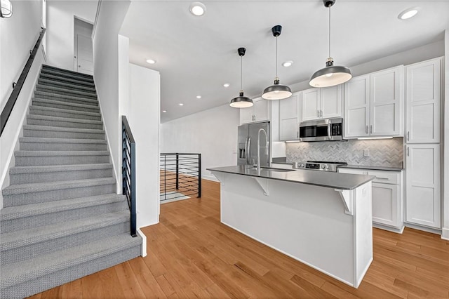 kitchen featuring white cabinetry, dark countertops, light wood finished floors, and appliances with stainless steel finishes