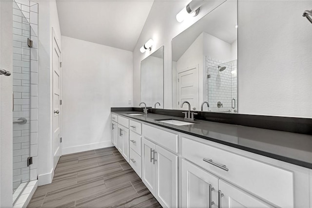 bathroom with a sink, wood finish floors, double vanity, and a shower stall