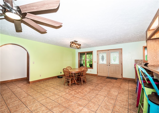 dining area with a textured ceiling, ceiling fan, light tile floors, and french doors