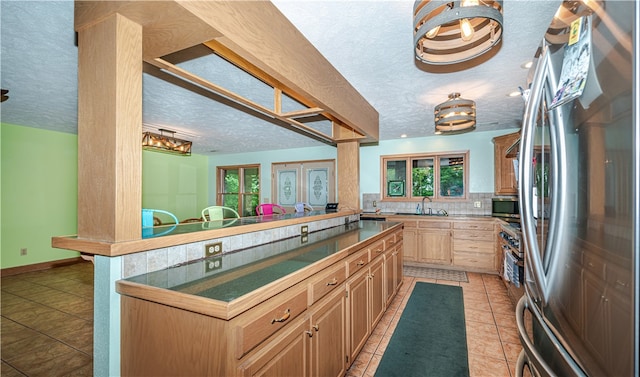 kitchen featuring a healthy amount of sunlight, tasteful backsplash, light tile floors, and stainless steel appliances