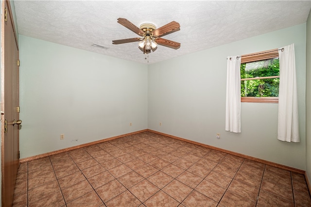 tiled empty room with ceiling fan and a textured ceiling