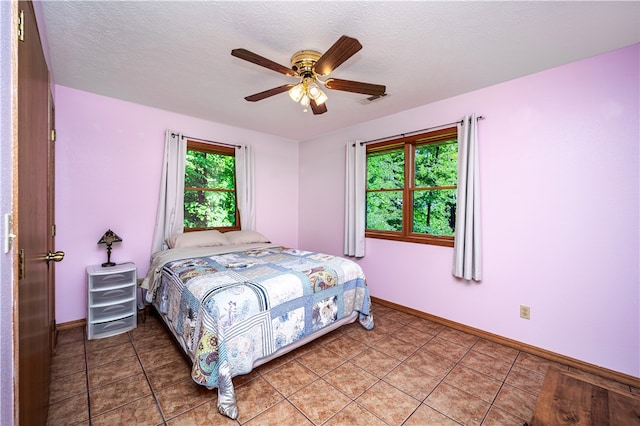 bedroom featuring tile flooring, ceiling fan, and a textured ceiling