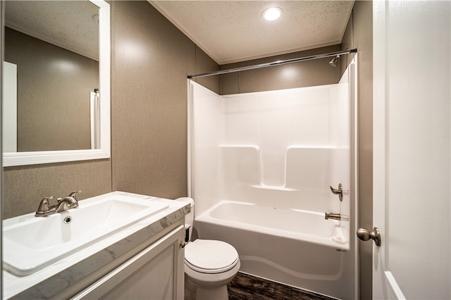 full bathroom with a textured ceiling, hardwood / wood-style flooring, shower / washtub combination, vanity with extensive cabinet space, and toilet