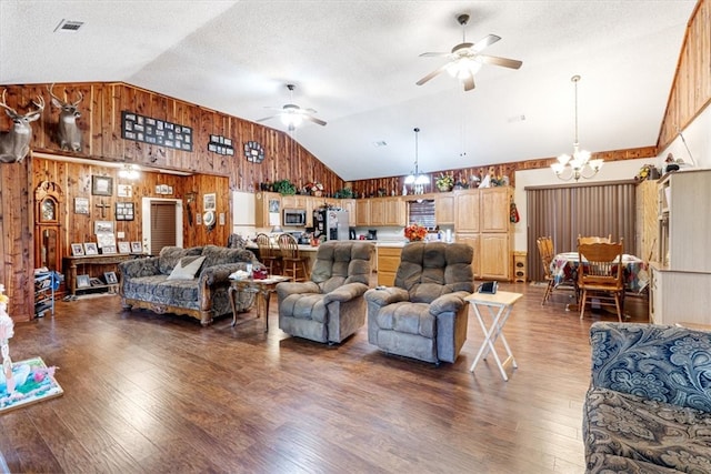 living room featuring wood walls, dark hardwood / wood-style floors, and ceiling fan with notable chandelier