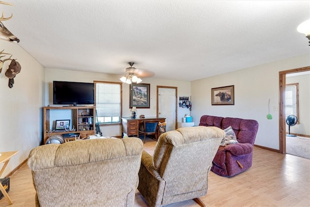 living room with a textured ceiling, ceiling fan, and light wood-type flooring