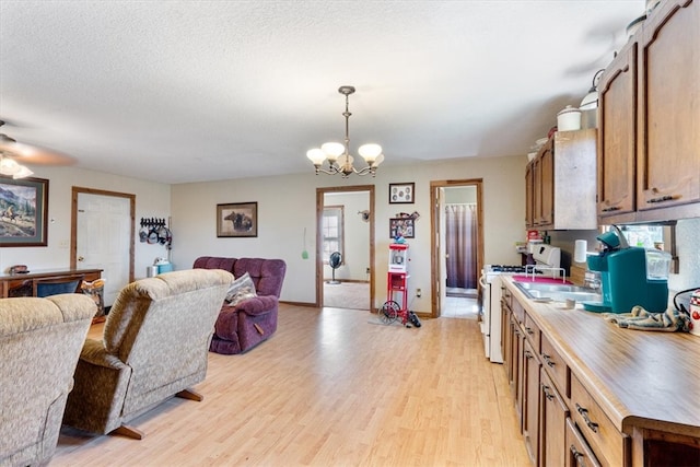 kitchen featuring an inviting chandelier, light hardwood / wood-style flooring, white range with gas cooktop, and pendant lighting