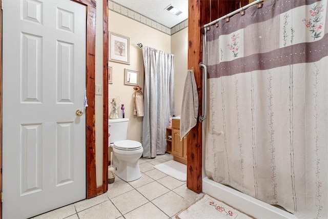 bathroom with tile flooring, toilet, vanity, and a textured ceiling