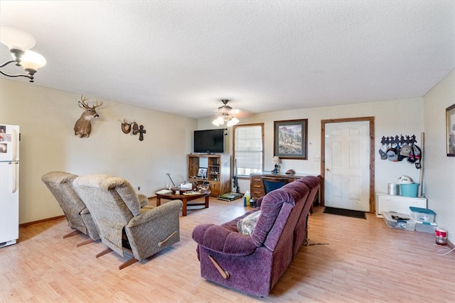 living room with a textured ceiling, light hardwood / wood-style floors, and ceiling fan