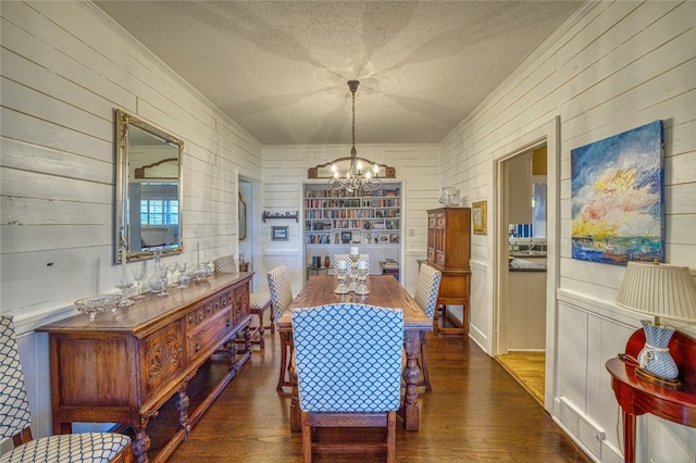 dining room featuring wood walls, a chandelier, and dark hardwood / wood-style floors