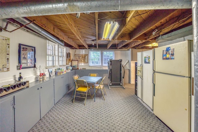 basement featuring light carpet and white fridge