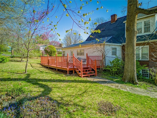 rear view of property featuring a wooden deck and a lawn