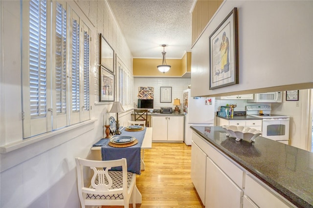 kitchen featuring white appliances, pendant lighting, white cabinets, light hardwood / wood-style flooring, and a textured ceiling